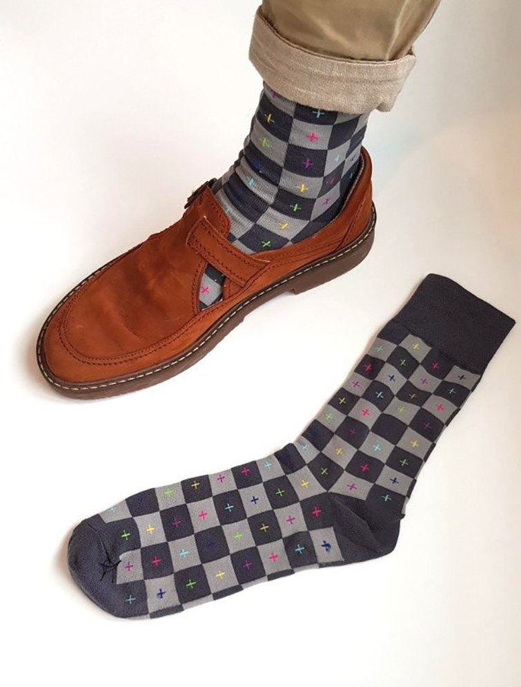 A man's foot wearing a Blender sock and loafer with an additional sock laying next to the foot